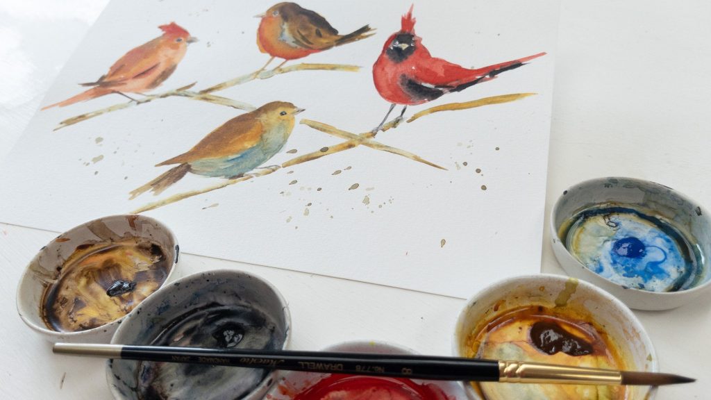 watercolor painting of robins and red cardinals with paints in ceramic dishes and Drawell round brush